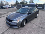 2015 Volkswagen Jetta SE FWD in gray, featuring alloy wheels and heated seats, parked on a paved area.