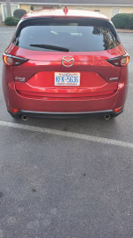 Back view of a red 2017 Mazda CX-5 SUV parked, showcasing its sleek design and dual exhaust.