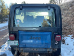 Rear view of a 1985 Jeep CJ7 with a Chevy 350 V8 engine parked on a snowy road.