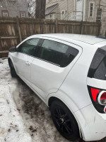 2016 Chevrolet Sonic LT hatchback in white with black rims parked in snowy area