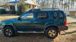 2000 Nissan Xterra SE RWD in green, ideal for first car or off-road activities, showing side view and tires.