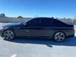 2014 BMW M5 in excellent condition with 70,000 miles displayed in a parking structure under clear blue skies.