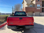 Red 2003 Ford F-150 parked, showcasing bedliner and well-maintained condition, ideal work truck.