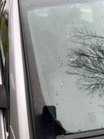 Close-up of the 2013 Ford Taurus windshield showing rain droplets and minor damage, indicating need for repair.