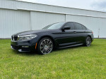 2017 BMW 540i xDrive M Sport in black, parked on grass with a building in the background