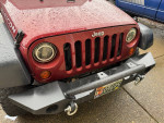 Front view of a red 2008 Jeep Wrangler Rubicon with rain droplets, showcasing its clean design.