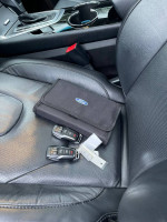 Key fob and owner’s manual on the leather seat of a 2016 Ford Edge Titanium, showcasing luxury features.