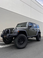 2015 Jeep Wrangler Rubicon in Tank Green with off-road accessories, parked in a lot