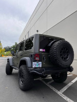 2015 Jeep Wrangler Rubicon in Tank Green parked, showcasing AEV accessories and rugged tires.