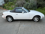 1994 Mazda Miata MX-5 in white color parked outdoors with some cosmetic wear and a convertible top.