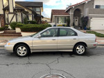 1997 Honda Accord Special Edition in silver, parked in front of a house, showcasing its side view.