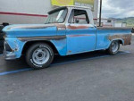 1965 Chevrolet shortbed truck with vintage patina, 350 engine, and classic styling parked in a lot.