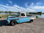 1965 Chevy short bed truck with vintage patina parked by a lake under clear skies