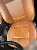 Interior view of 2006 BMW X3 showing worn leather seat and steering wheel.