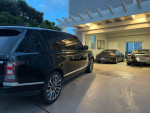Black Land Rover Range Rover Autobiography parked in a luxury garage with high-end vehicles.