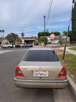 Rear view of a well-maintained Mercedes-Benz C280 parked on a quiet street, showcasing its original paint and leather interior.