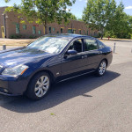 2007 Infiniti M35 in Crimson Roulette color parked outdoors with trees in the background.