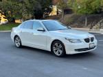 2010 BMW 5 Series 528i sedan parked, showcasing its sleek design and excellent condition with low mileage.