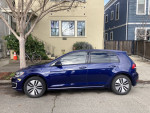 Side view of a 2019 Volkswagen Golf in Atlantic Blue, parked on a street with a tree in the background.