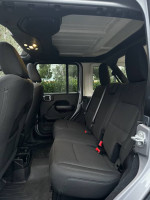 Interior view of 2019 Jeep Wrangler Sport 4WD showing spacious back seat area with black upholstery.