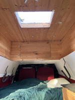 Interior of a spacious 2003 camper van with wood paneling and a skylight, perfect for road trips.
