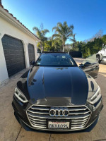 2015 Audi A5 in grey with a sleek black interior, parked in a driveway under clear blue skies.