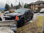 2014 Ford F350 Super Duty 4x4 truck with plow and winter tires parked on a residential street.