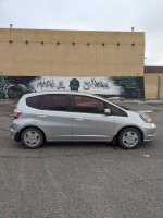 2013 Honda Fit in silver color parked in front of a mural, showcasing its compact design and cargo space.