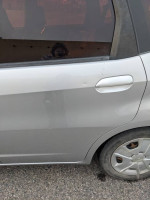 Side view of a 2013 Honda Fit showing door and tire, highlighting its practical design and spacious cargo area.