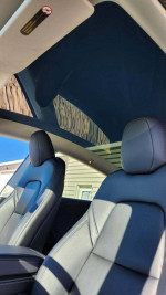 Interior view of a 2023 Tesla Model Y with black leather seats and panoramic roof