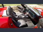 Interior of a red 2006 Pontiac Solstice with black leather seats and open roof