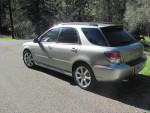 2006 Subaru WRX wagon parked on a road surrounded by trees, showing sleek design and sporty features.