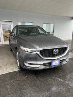 2019 Mazda CX-5 Signature in grey parked outside a dealership, featuring a clean exterior and modern design.