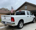 White Dodge Ram 1500 4x4 truck with 5.7 Hemi engine parked outside a house with an American flag.