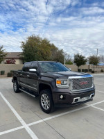 2015 GMC Sierra Denali Z71 4WD in silver, parked outdoors with clear sky, showcasing premium design and features.