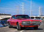 Stunning 1968 Mercury Cougar in vibrant red parked on a street with graffiti.