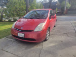 2006 Toyota Prius in red, parked on driveway with black leather seats and backup camera, showing wear and mileage.