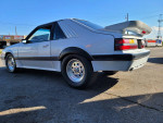 1986 Ford Mustang Foxbody with a V8 engine, sleek design, and racing features, parked outdoors.