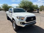2022 Toyota Tacoma SR 4WD in white color, parked on a gravel road with greenery in the background.