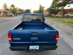 Rear view of a blue 2008 Ford Ranger showing its clean condition and new tires, parked on a residential street.