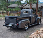 1950 Ford F1 pickup truck with a flathead V8 engine and new chrome wheels in a scenic outdoor setting.
