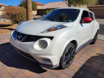 White Nissan Juke Nismo edition parked, showcasing its sporty design and sleek profile with black alloy wheels.