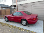1997 Mercedes-Benz SL500 in red with cosmetic wear, parked on a driveway.