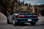 Rear view of a 1997 Chevrolet Camaro Z28 convertible parked on a scenic road.