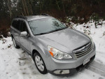 2010 Subaru Outback in silver parked on snow-covered ground, showcasing its premium features and clean condition.