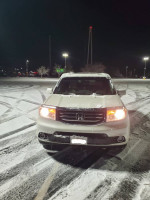 2015 Honda Pilot Touring 4WD parked in snow, showcasing excellent winter performance with new tires and good condition.