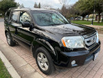 2011 Honda Pilot EX FWD in black parked on a street, showcasing its smooth design and shiny paint.