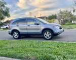 Side view of a 2011 Honda CR-V EX-L SUV parked on the street, showcasing its blue metallic color and gray leather interior.
