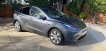 2023 Tesla Model Y Long Range AWD in gray, parked in a driveway, showcasing its sleek design and contemporary features.