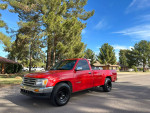 1993 Toyota T100 SR5 4WD pickup truck in red, parked on a street surrounded by trees.
